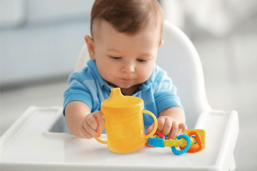baby holding a yellow sippy cup