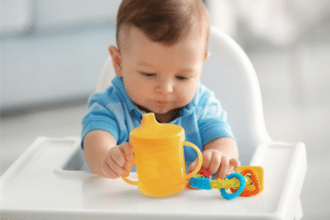 baby holding a yellow sippy cup
