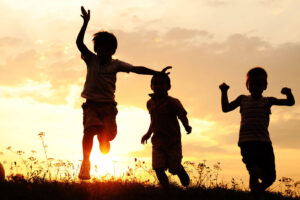 group of happy children playing on meadow