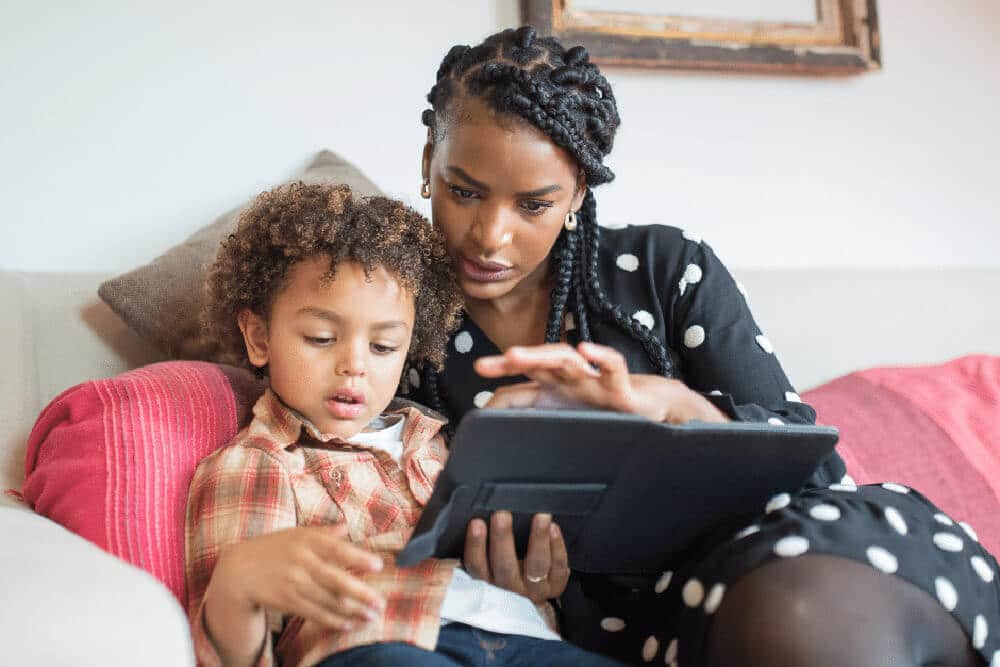 child looking at a tablet with mother